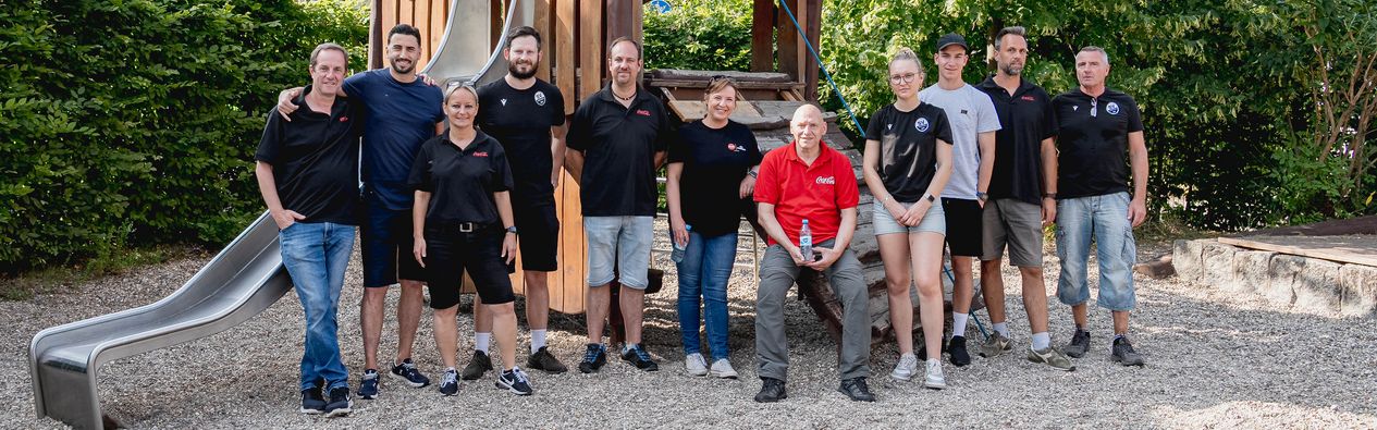 Gruppenfoto der Helfer des SV Sandhausen und des Partner Coca Cola vor einem Spiel- und Klettergerät der KiTa "Kleine Pusteblume" in Heidelberg.