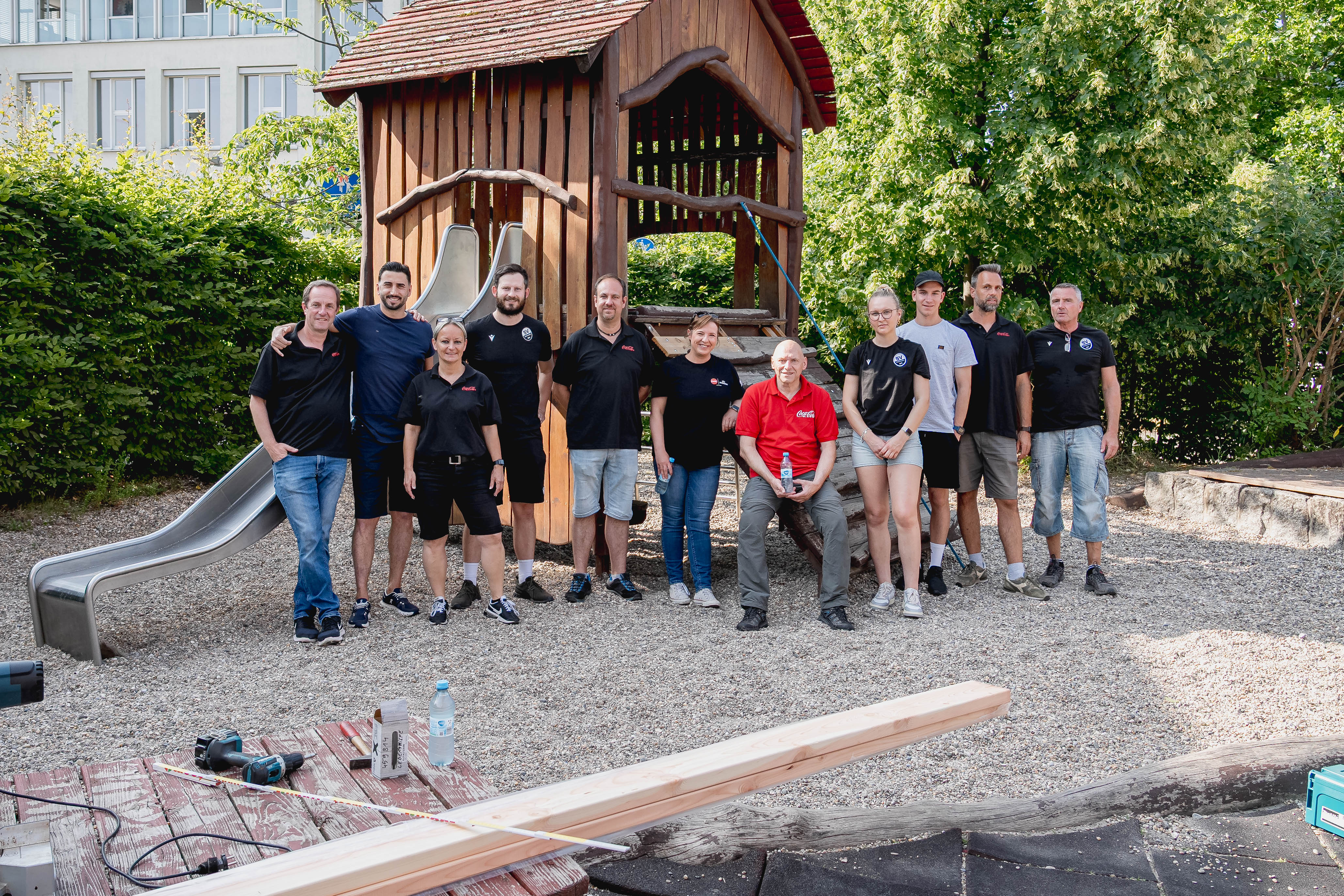 Gruppenfoto der Helfer des SV Sandhausen und des Partner Coca Cola vor einem Spiel- und Klettergerät der KiTa "Kleine Pusteblume" in Heidelberg.